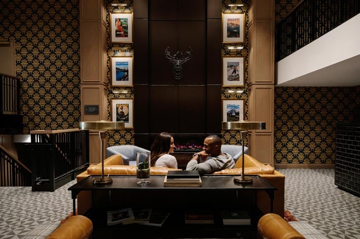 Two people sit in a luxury hotel lobby with artwork adorning the walls
