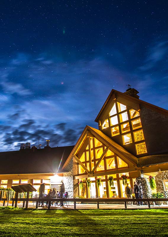 Talkeetna Alaskan Lodge at night time, with light glowing from a tall lounge area.
