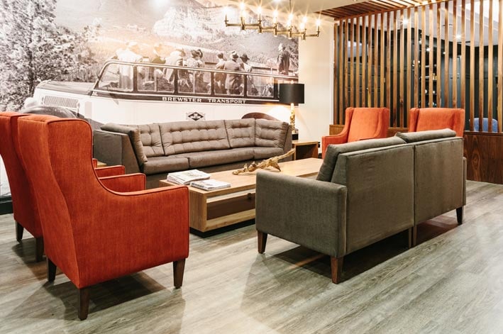 A hotel lounge with orange and grey chairs and sofas