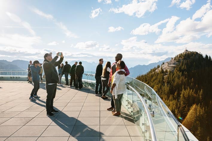 Groups on people take scenic photos at the top of the Banff Gondola