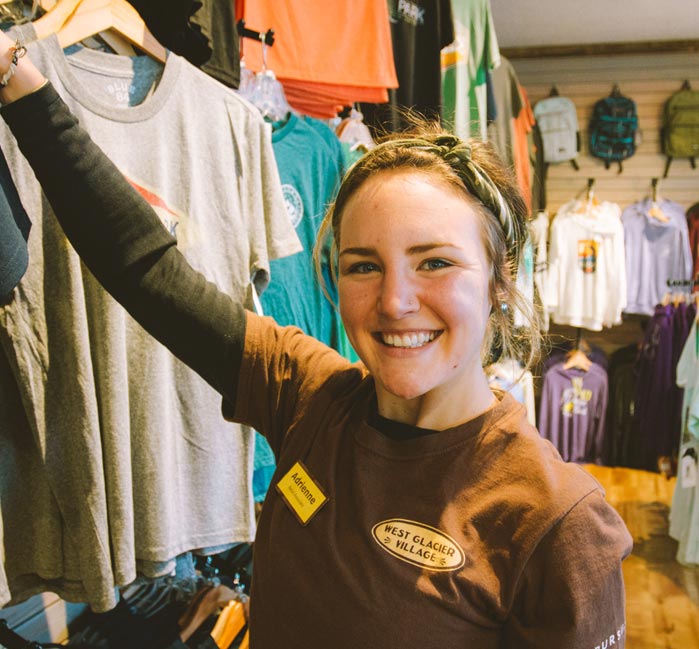 A retail worker hangs up t-shirts in a shop.
