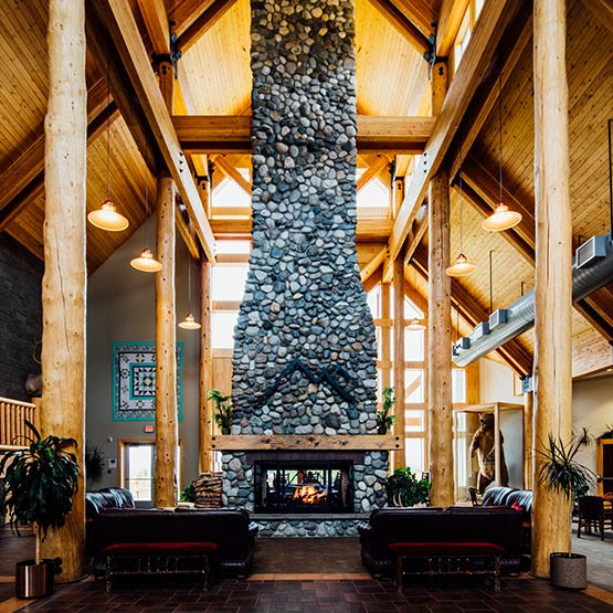 A tall rough stone fireplace stands in the center of the Talkeetna Alaskan Lodge lobby.