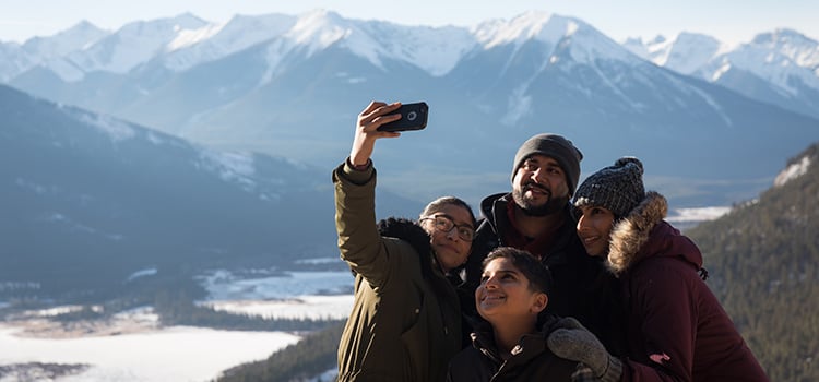 A family poses for a selfie with mountains in the background
