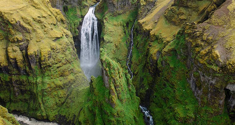 A waterfall crashes between grassy cliffs.