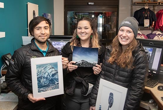 A group of workers hold photos of landscapes and wildlife.